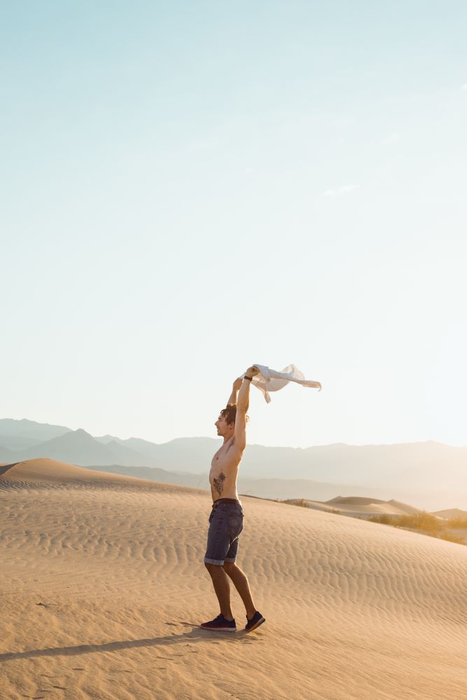 Side view of active young man without shirt enjoying wind in dry Death Valley