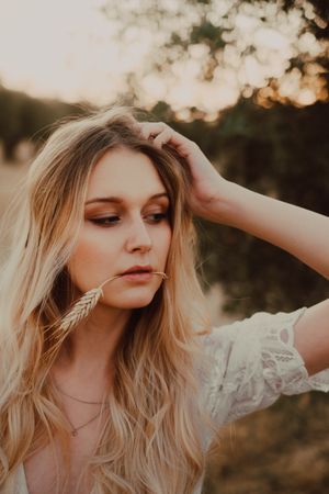 Thoughtful beautiful woman with flowing hair and straw in mouth