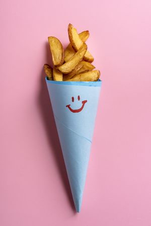 French fries in blue cone on pink background
