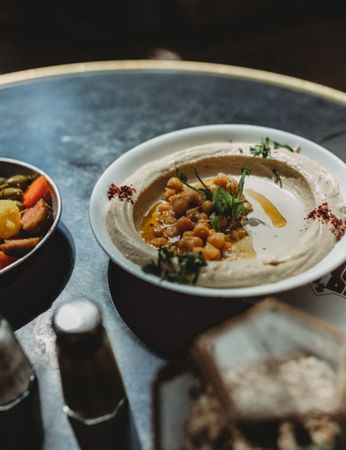 chickpeas hummus in plate close to vegetables plate