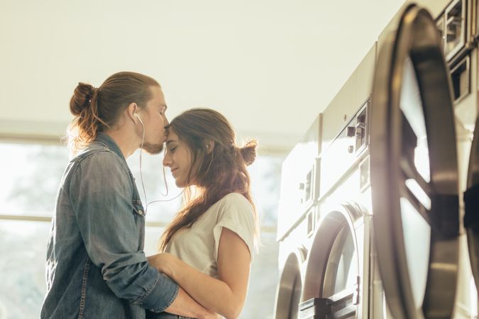 Couple standing in a laundry room holding each other listening to music