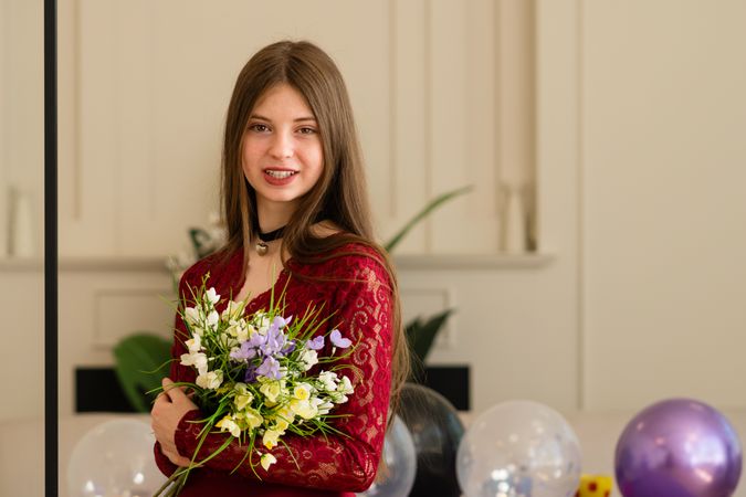 Teen girl in red lace dress holding bouquet of flowers