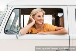 Woman resting head on hand leaning out of vehicle window 43BnV5