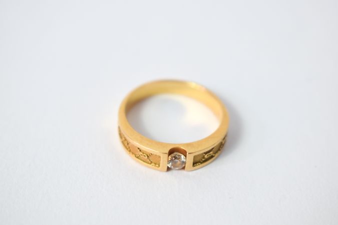 One diamond gold ring on plain table with copy space