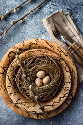 Top view of decorative eggs in delicate nest on rustic brown plate on table