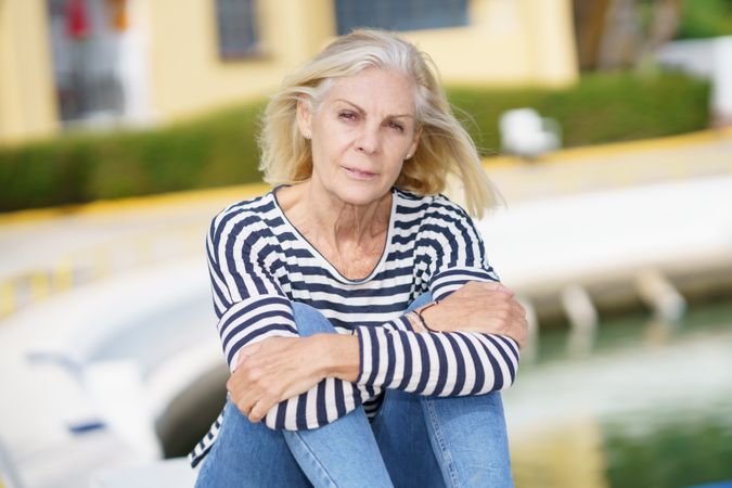 Portrait of older female relaxing on a pier on sunny day