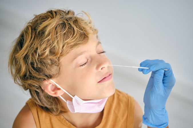 Crop nurse taking COVID test from boy in clinic