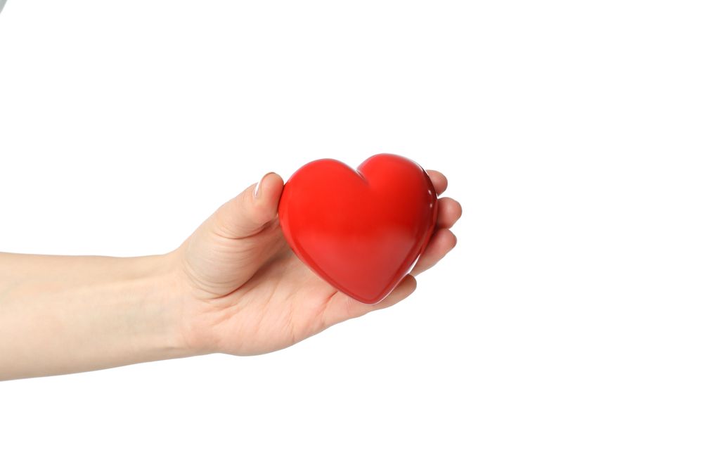 Female hand holds heart, isolated on plain background