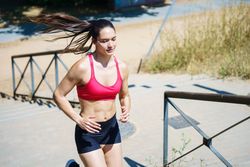 A woman in sportswear is jogging outdoors, demonstrating commitment to fitness, strength, and determination