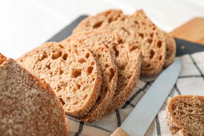Composition with bread, knife, kitchen towel and cutting board on wooden background, closeup and space for text