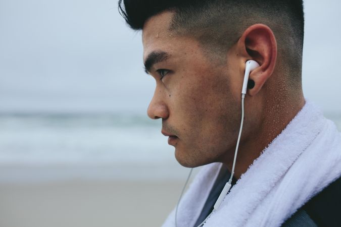 Close up of young asian man with earphones and towel around his neck