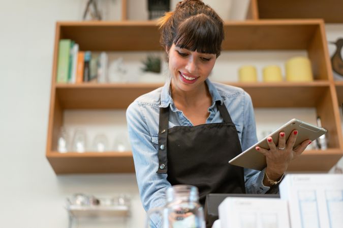 Woman working at cafe with digital tablet in hand