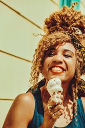 Close up of smiling Black female smiling with an ice cream cone in the sun, vertical, copy space