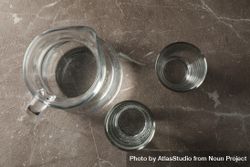 Top view of glasses of water and jug on grey marble table 48Ygjb
