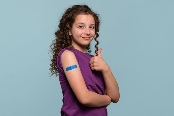 Girl giving thumbs up after receiving vaccine