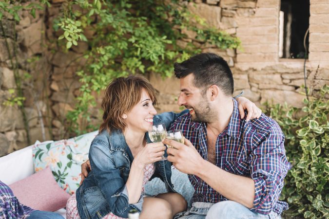 Couple sitting on a terrace while bonding and toasting with glass of wine