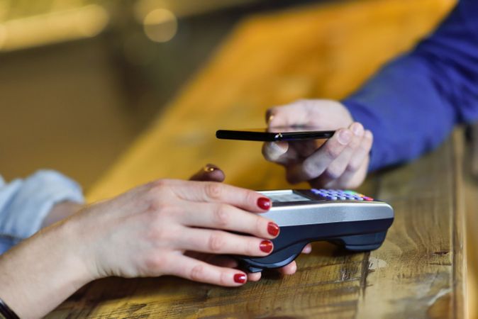 Man paying with smartphone on bar