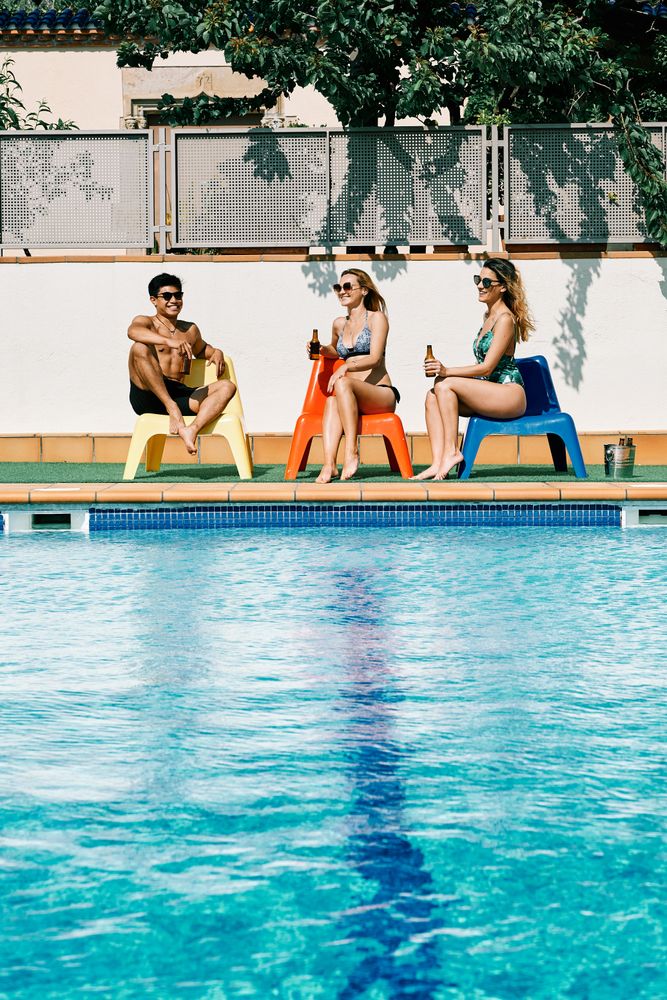 two young and women looking at a handsome man by the pool