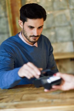 Man in sweater paying using smartphone