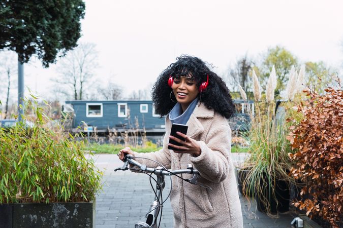 Black woman with smartphone on bicycle
