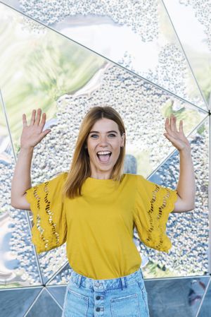 Young cheerful woman posing with hand in air