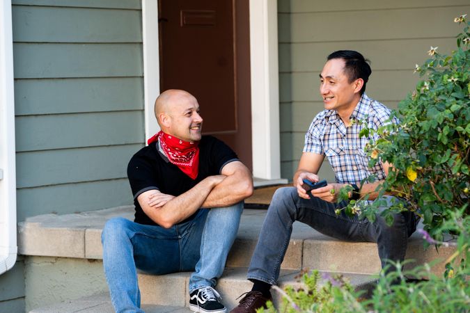 Handsome married couple talking and smiling sitting on front porch