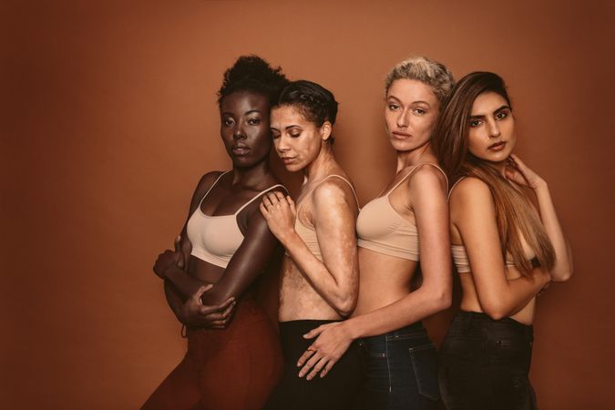 Group of four diverse young women on brown background