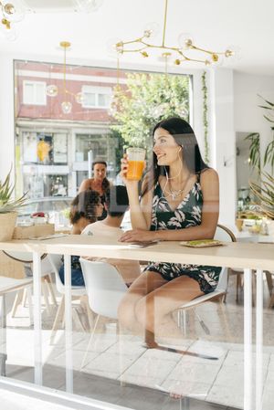 Lady with healthy drink listening to music in cafe
