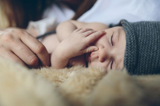 Baby sleeping on a blanket with her mother's hand