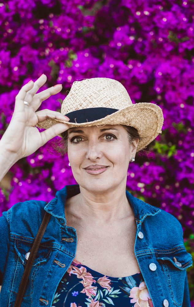 Woman standing near a wall with flower shrubs