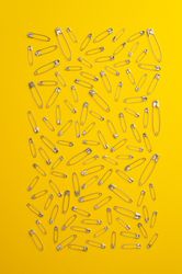 Scattered safety pins on yellow background