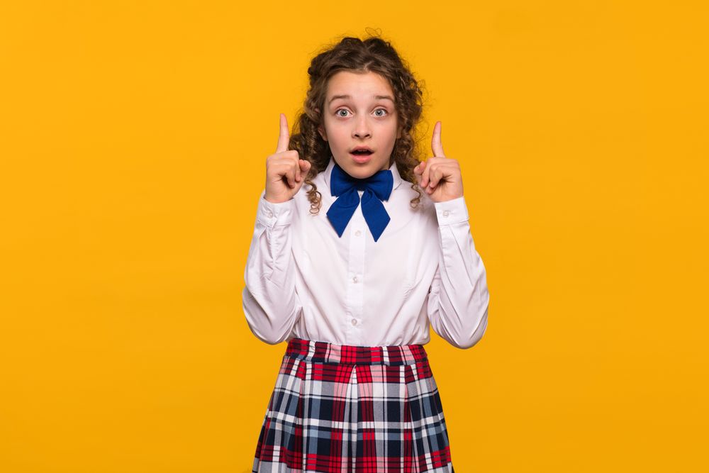 Girl with both index fingers raised, surprised expression.