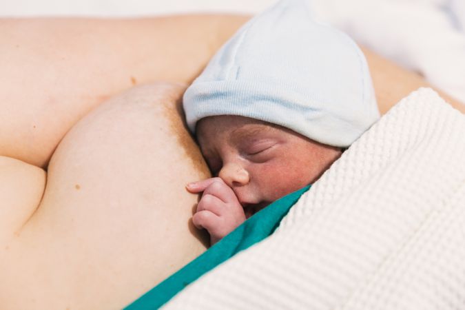 Cute newborn baby sleeping on his mother's chest in the hospital room.