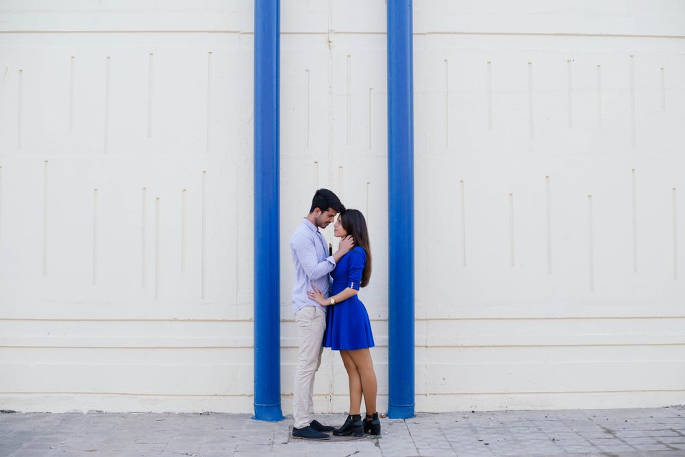 Amorous couple standing against white wall with blue columns