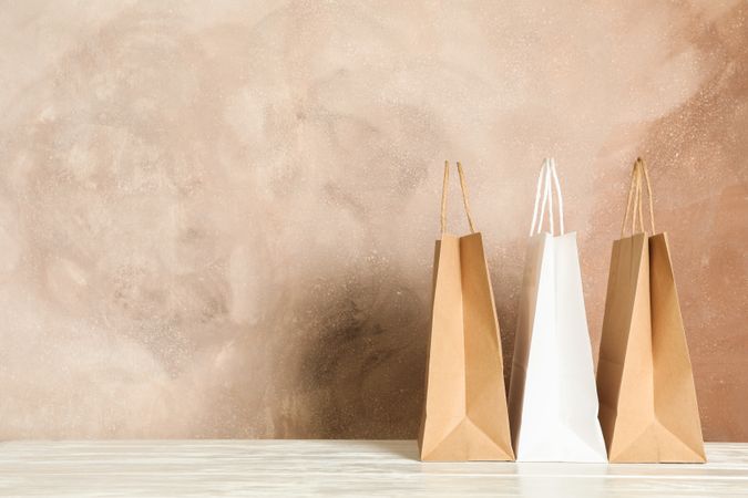 Paper bags on table against brown background, copy space