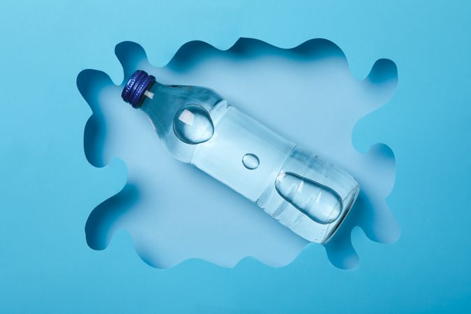 Looking down at full water bottle in swirly cut out blue frame