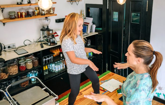 Mother dancing with her daughter while working in a coffee shop