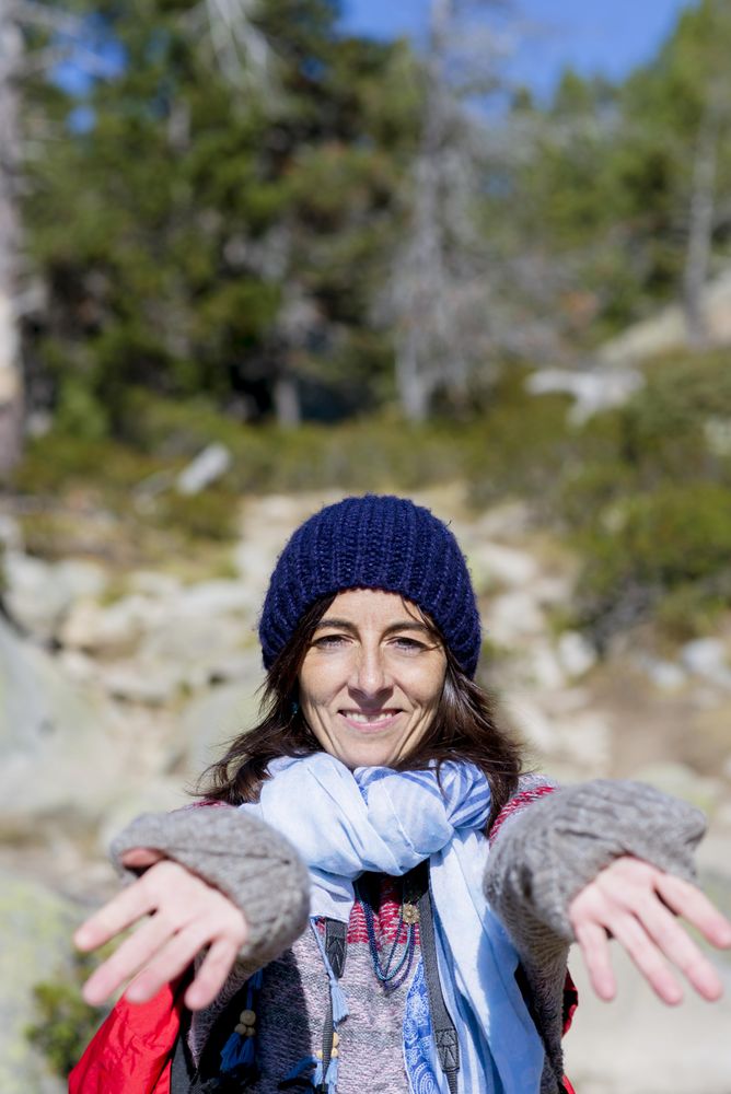 Smiling female looking at camera in the woods with arms outstretched