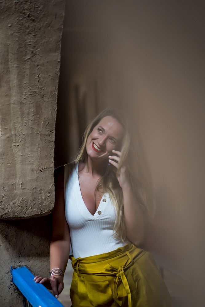 Smiling woman using smartphone on old balcony