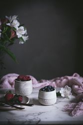 Raspberries and blueberries on glasses on table
