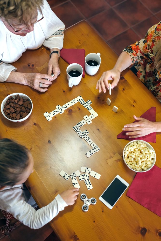 Top view of three female generations playing domino