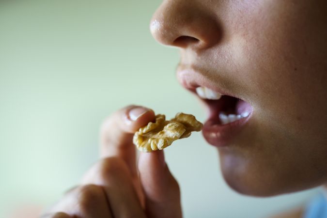 Side view of anonymous teenage girl about to bite into a delicious walnut
