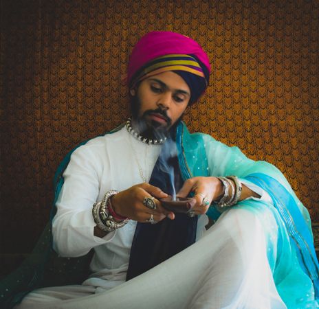 Man wearing turban and holding incense burner indoor
