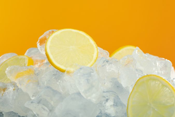 Pile of ice on orange background with sliced oranges