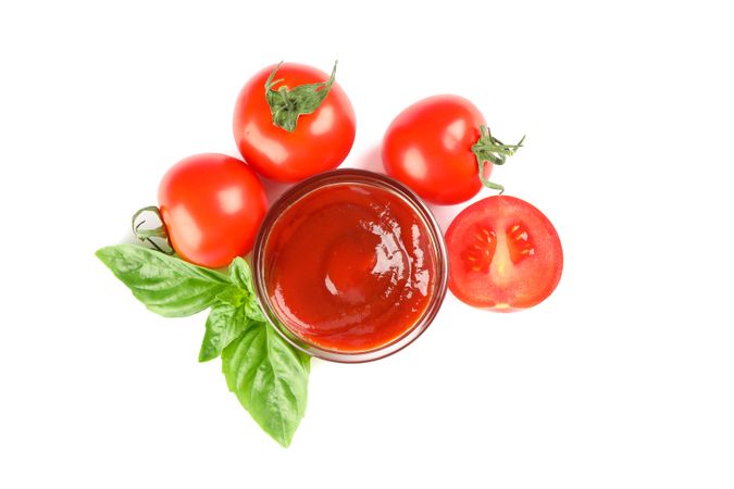 Fresh cherry tomatoes with basil and souce isolated on light background, top view. Ripe vegetables