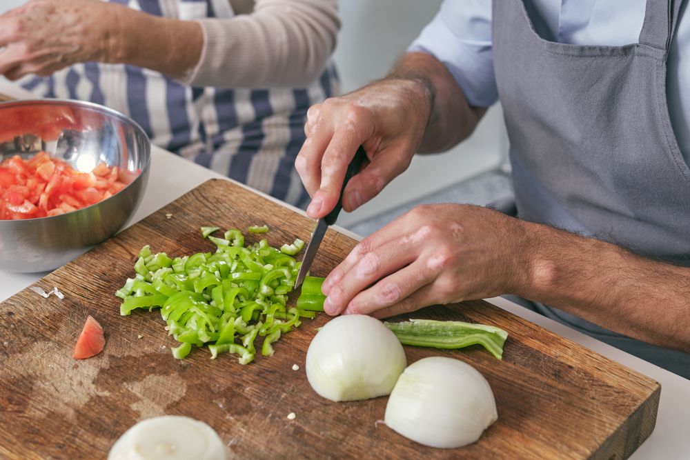 Unrecognizable man cutting green pepper