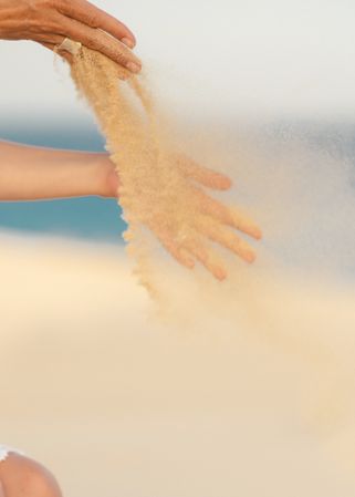 Woman releasing sand in hands in wind