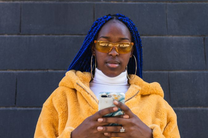 woman in trendy outfit browsing cellphone in city