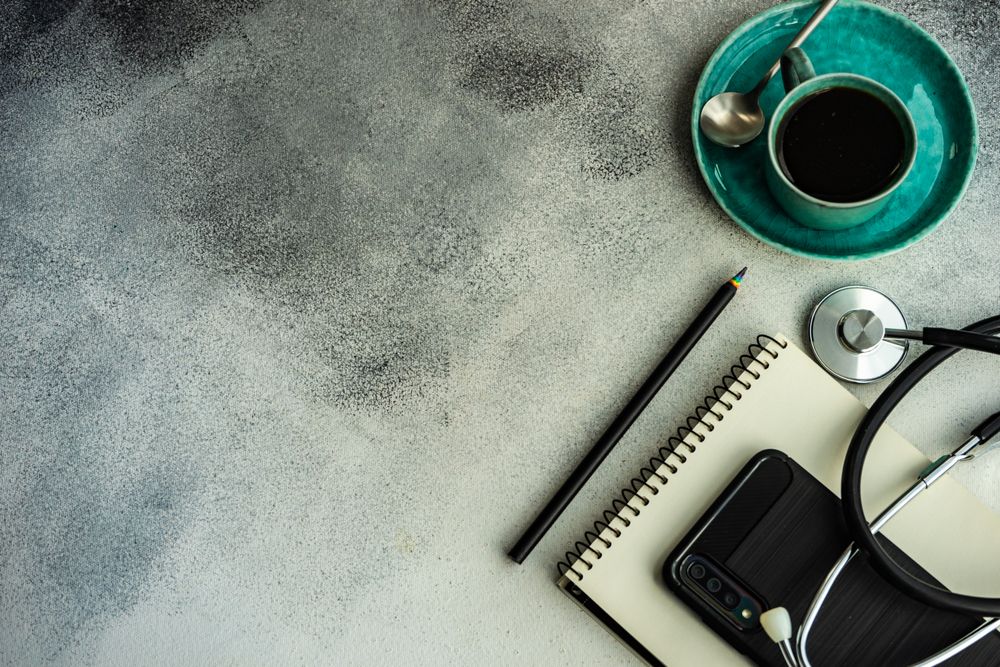 Top view of coffee cup with stethoscope, phone and notepad with copy space