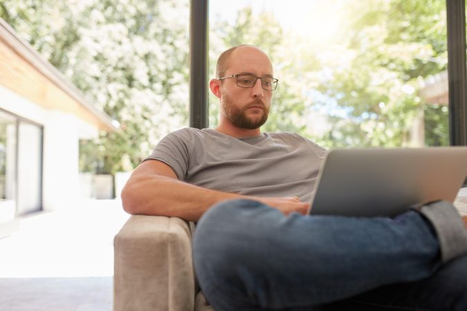 Man sitting on a sofa and working on laptop in his living room
